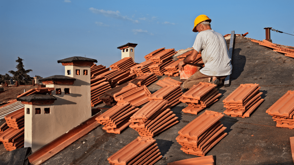Worker reinstalling tiles after underlayment replacement